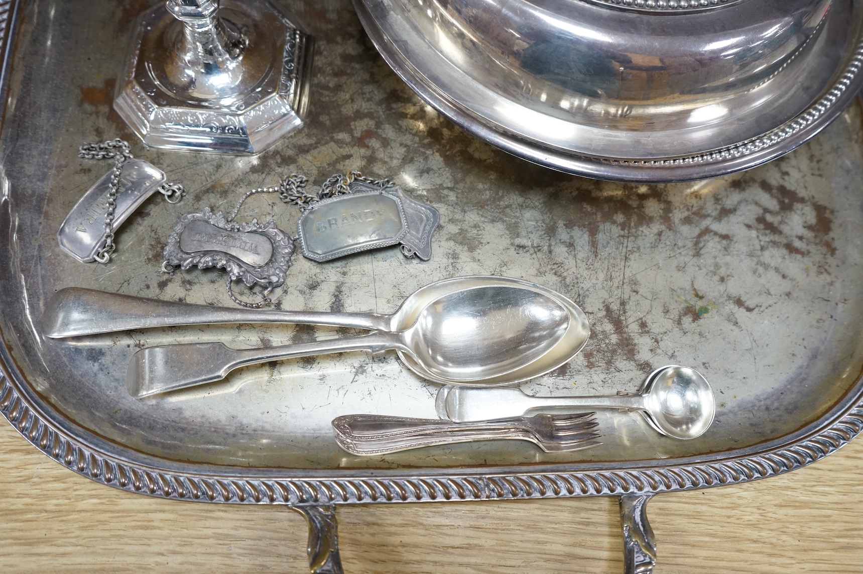 A pair of white metal candlesticks, a silver plated teapot circular tureen and cover spoons and forks and four spirit labels and large tray. Tray 73cm wide